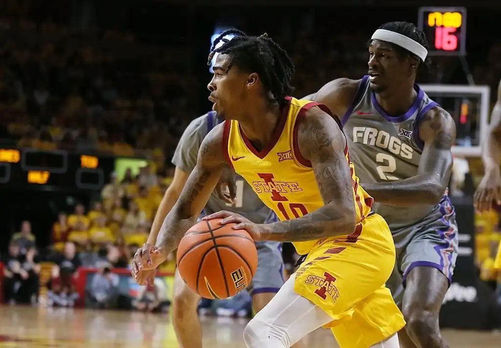Iowa State basketball player drives toward the basket while being closely defended by a TCU player.