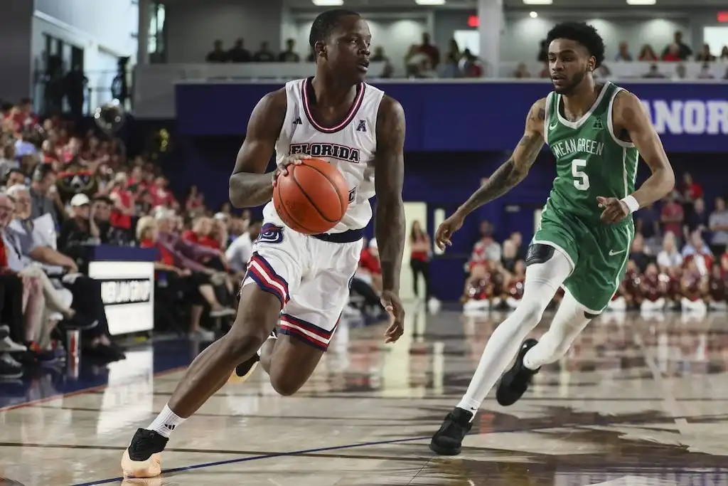 NCAAB 5 Florida Atlantic basketball player drives down the court while being chased by a North Texas defender.
