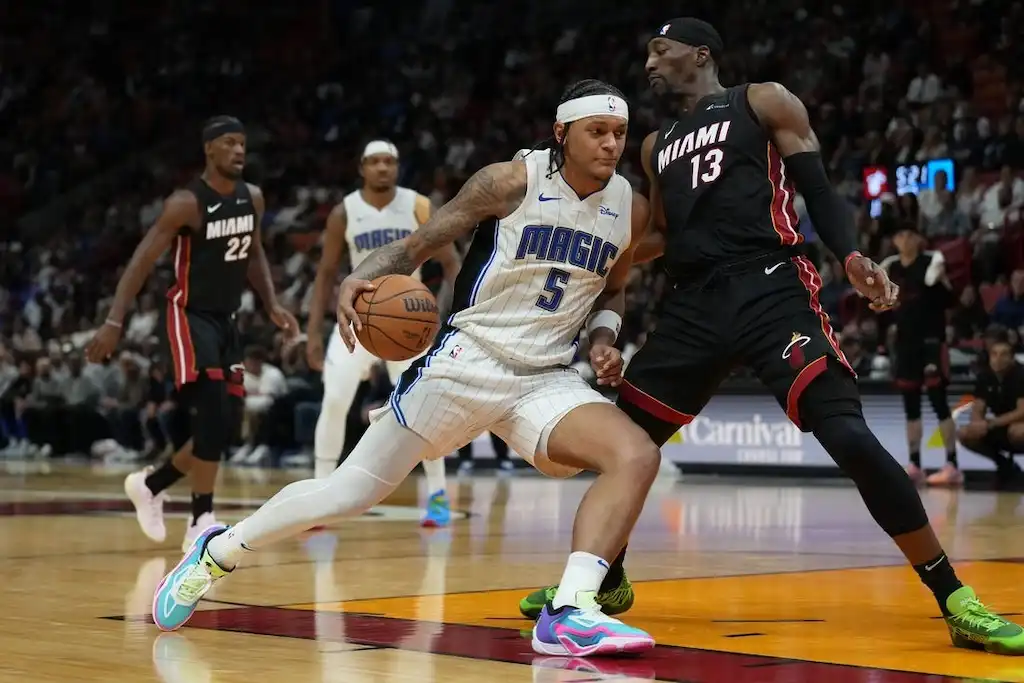 An Orlando player drives to the basket while being tightly defended by a player.