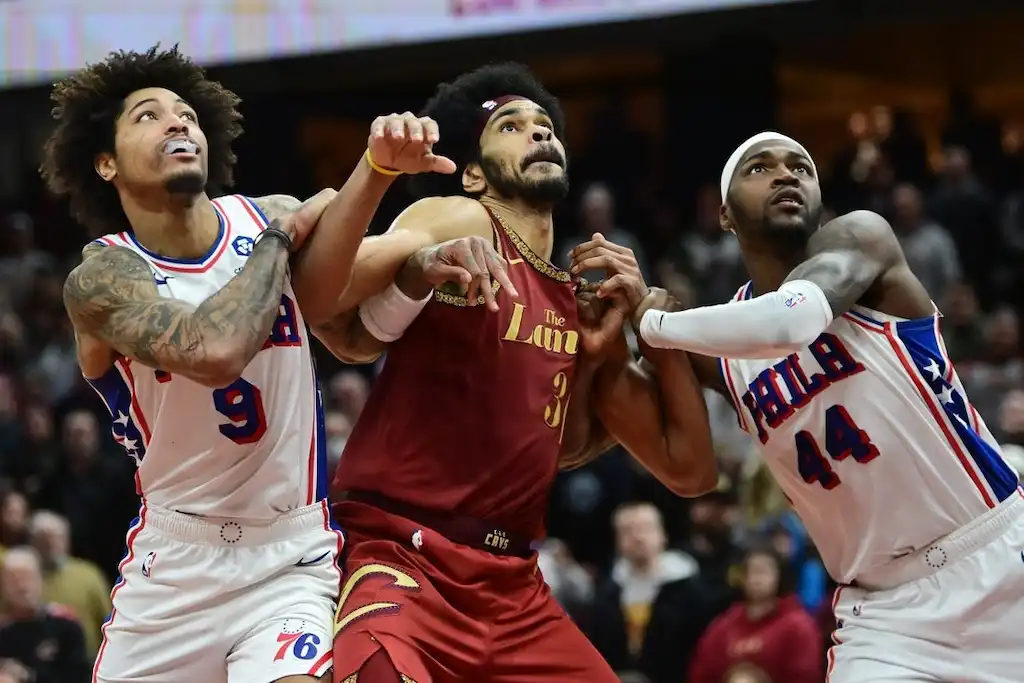 A Cleveland Cavaliers player battles for rebounding position between two Philadelphia 76ers players.
