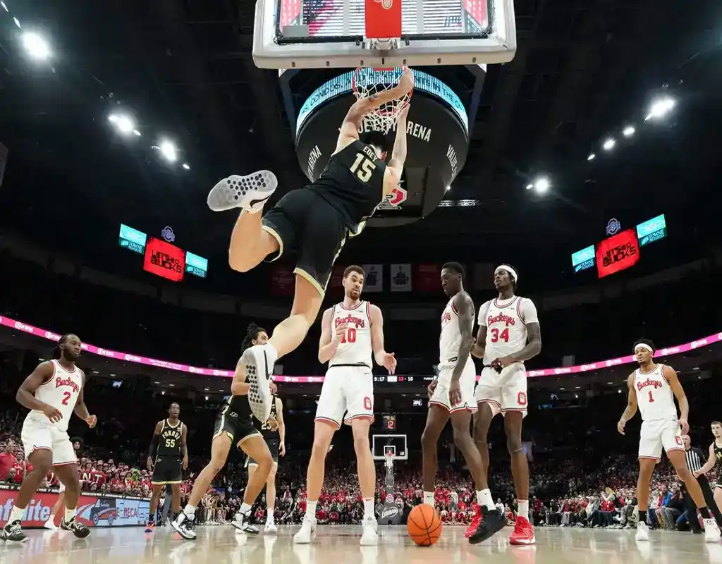 Purdue Boilermakers player dunks over Ohio State defenders during intense NCAA basketball game