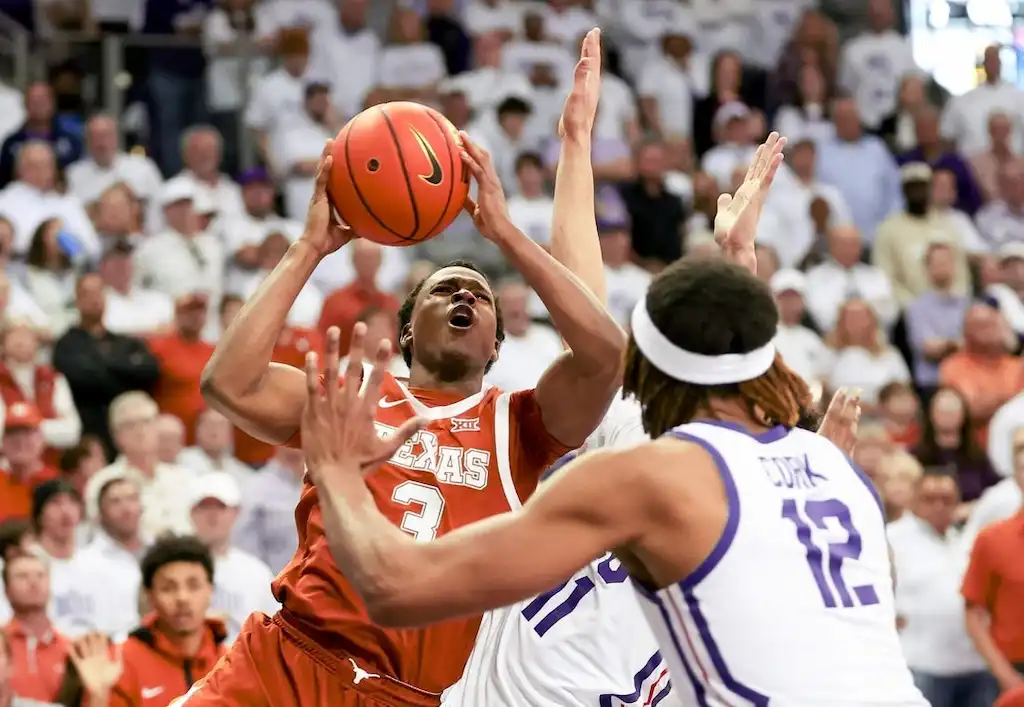 A Texas Longhorns player drives to the basket with intensity.