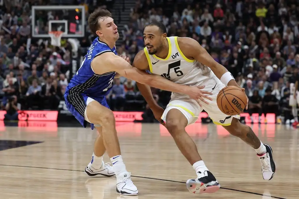 4 A Utah Jazz player drives toward the basket while being closely guarded by a defender.