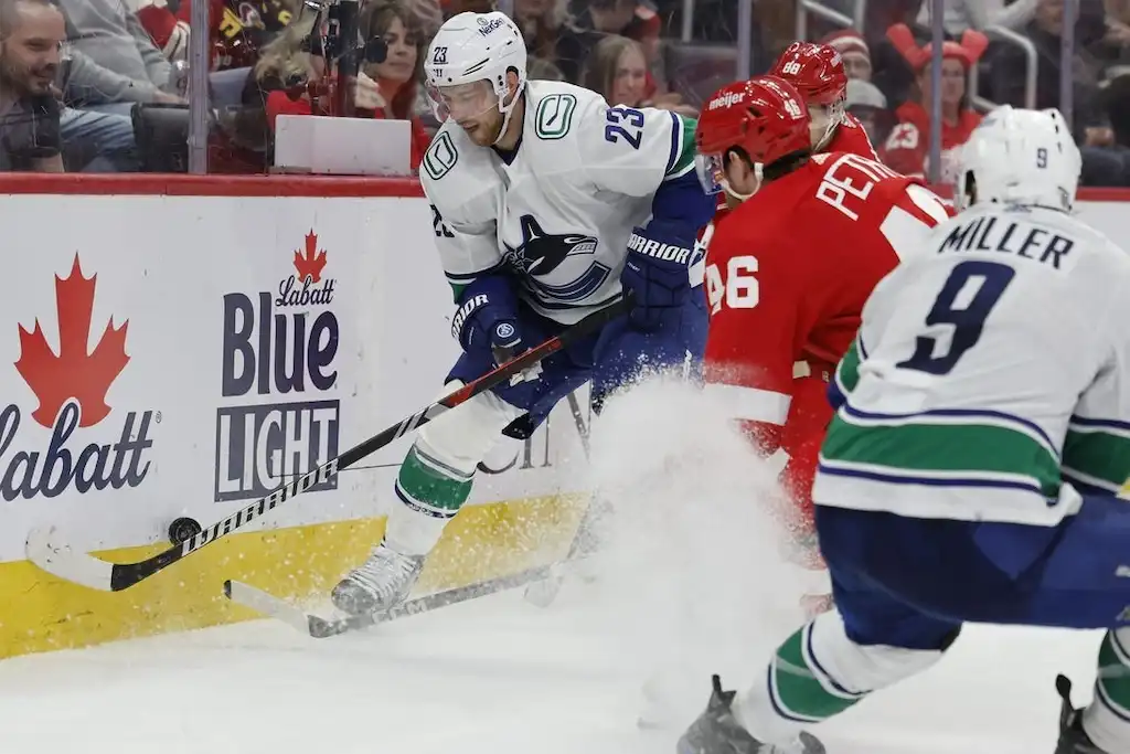 A Vancouver Canucks player controls the puck along the boards.