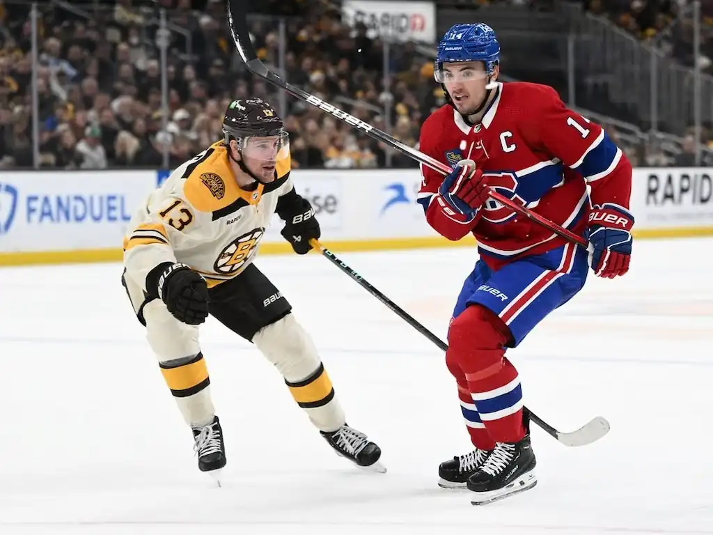 Montreal Canadiens captain skates alongside a Boston Bruins player.