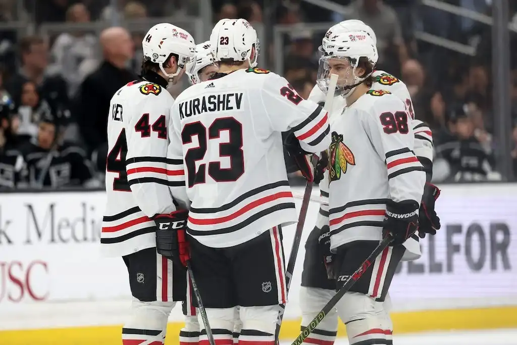 NHL 2 Chicago Blackhawks players huddle on the ice during a break in play.