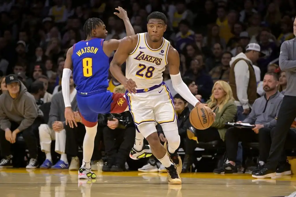 Los Angeles Lakers player dribbles the basketball up the court past a defender.