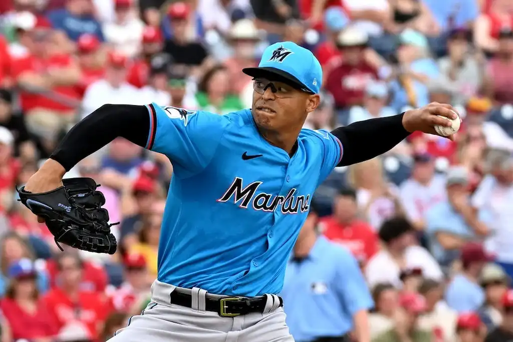 Miami Marlins pitcher in a blue jersey winds up to throw a pitch during a game.