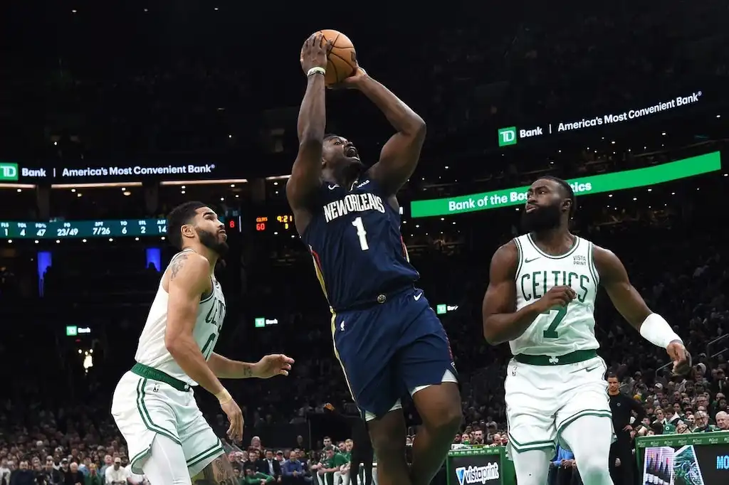 New Orleans Pelicans player goes up for a shot against two Boston Celtics defenders.