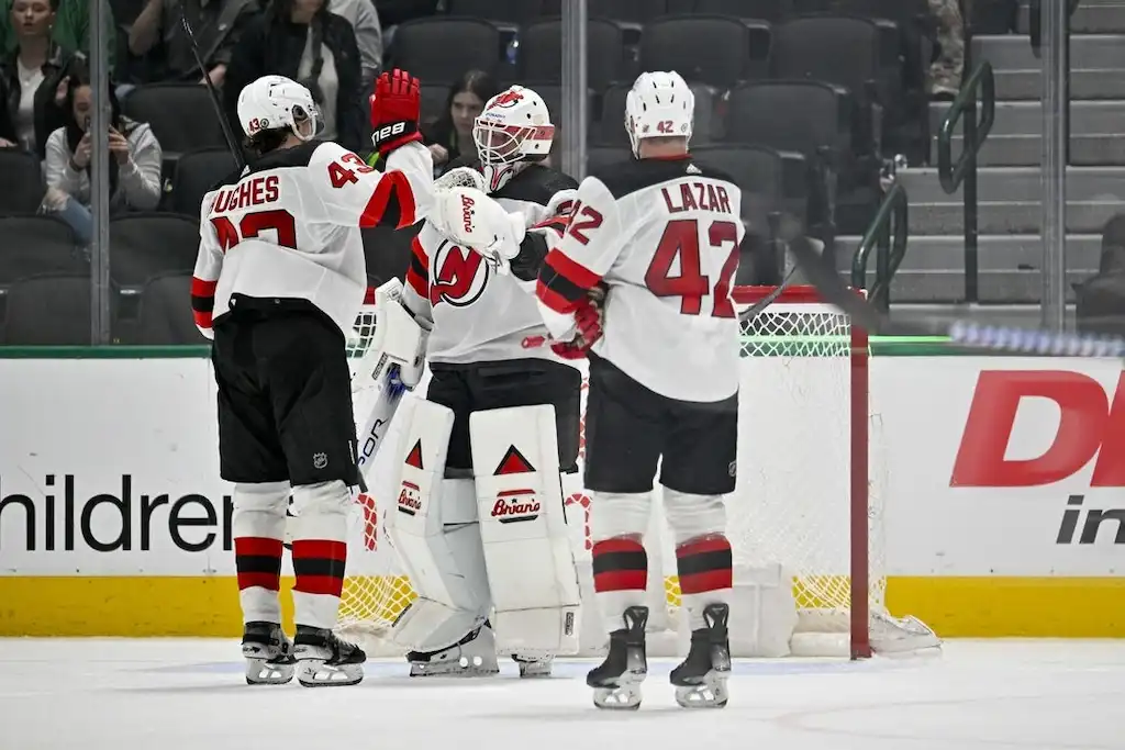 New Jersey Devils players celebrate on the ice in front of their goal.