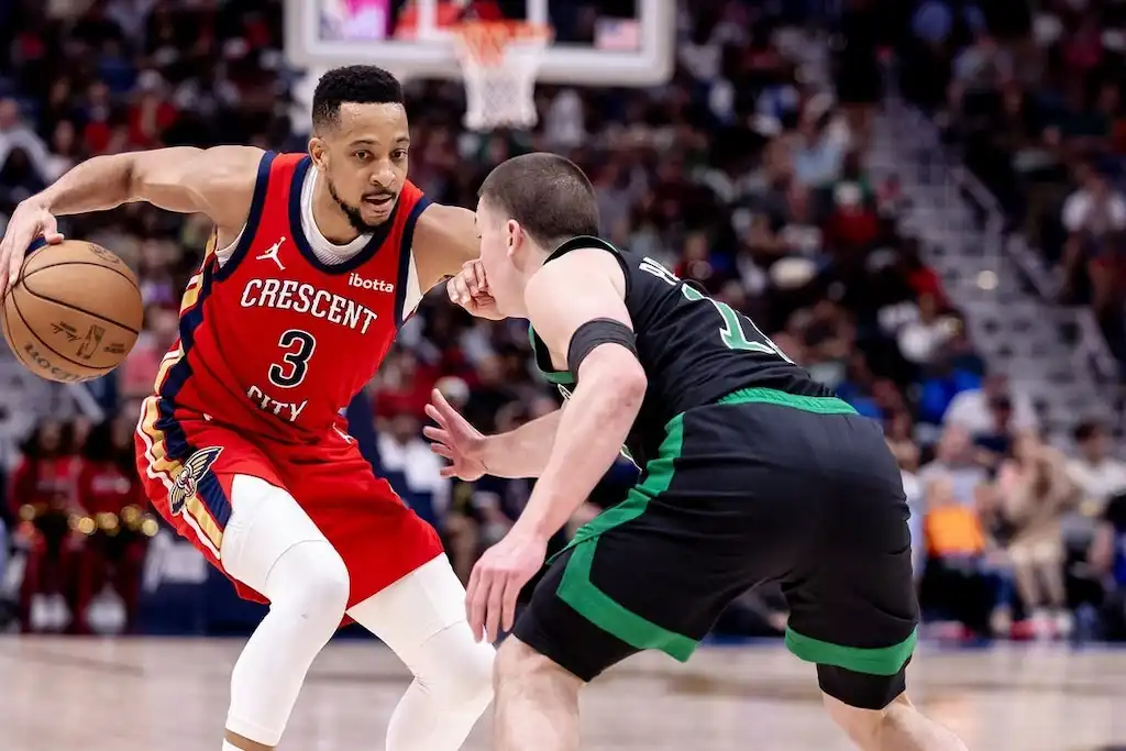 NO Pelicans player dribbles the ball while being closely guarded by a defender.