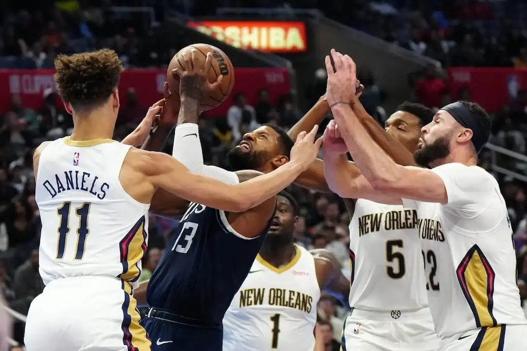 A basketball player attempts a contested shot while surrounded by multiple NO Pelicans defenders.