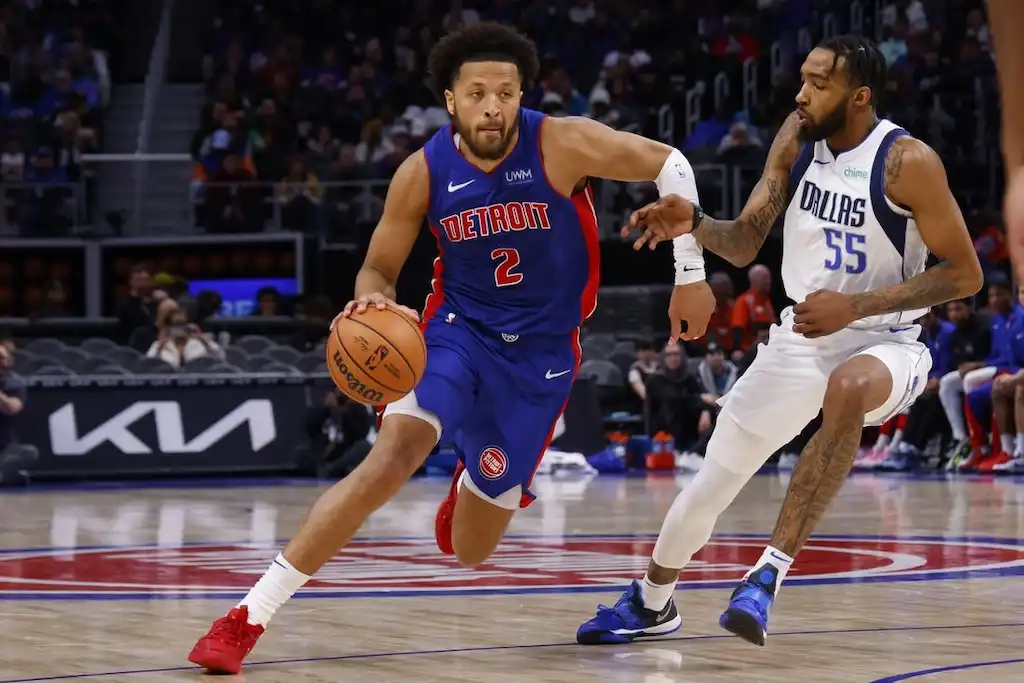 Detroit Pistons player drives past a Dallas Mavericks defender.