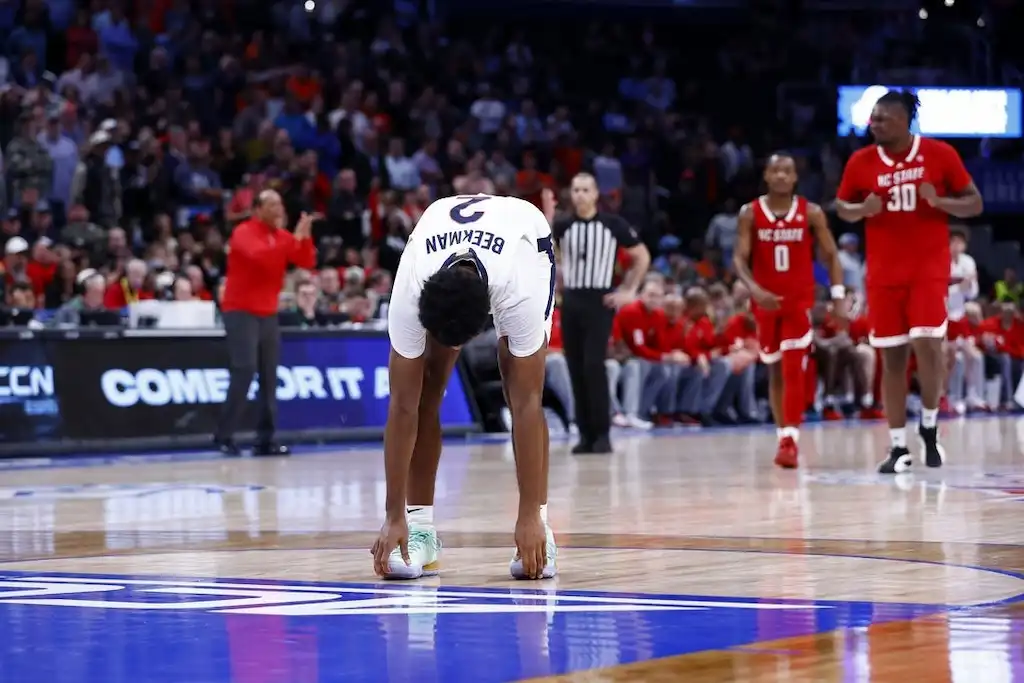 A University of Virginia Cavaliers player bends over in frustration at midcourt.