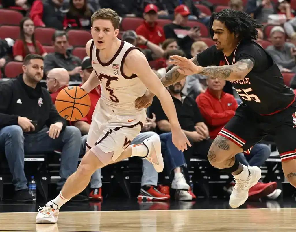 Virginia Tech player dribbles past Louisville defender in an intense college basketball matchup