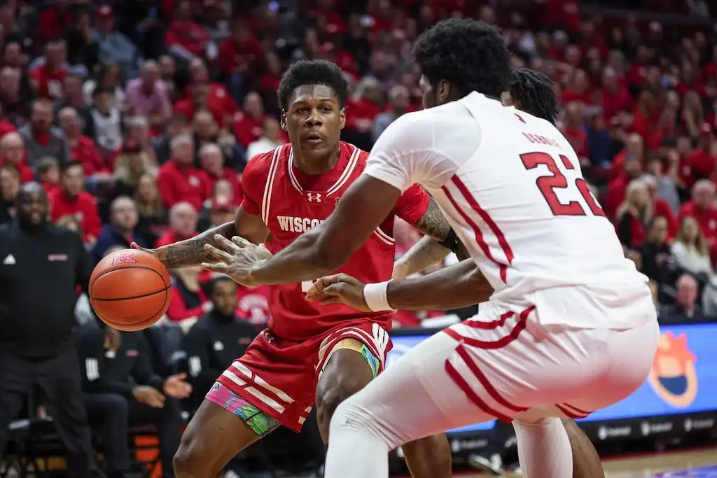 NCAAB 1 A Wisconsin basketball player looks to make a play while being tightly defended by two players.