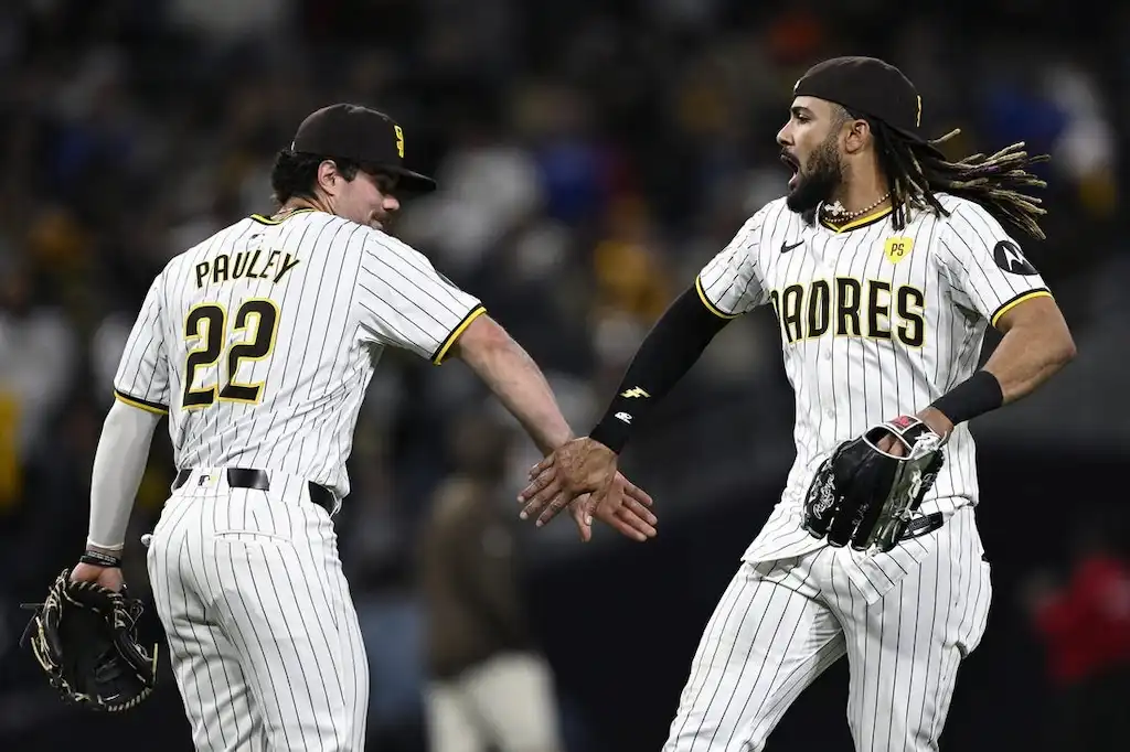 Two San Diego Padres players celebrate with a high-five on the field.
