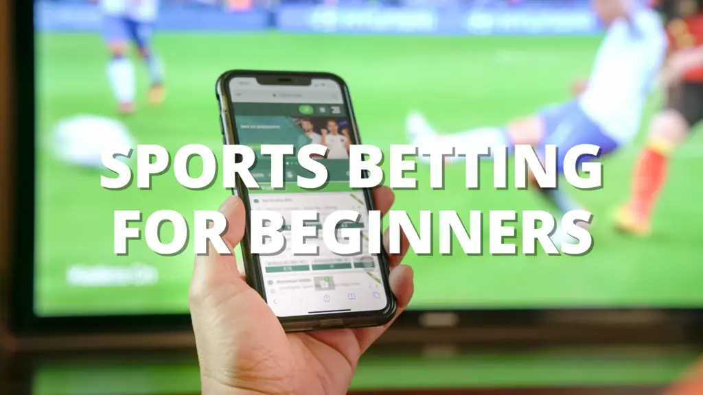Person holding a smartphone with a sports betting app in front of a TV showing a soccer match, with text reading "Sports Betting for Beginners." 2/2