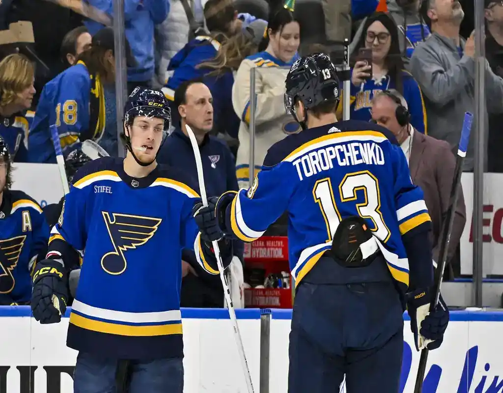 St. Louis Blues players tap gloves near the bench during their April 10, 2024 game against the Chicago Blackhawks