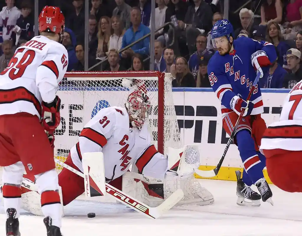 Carolina Hurricanes goalie #31 making a save as New York Rangers forward #96 approaches the net in front of a packed crowd