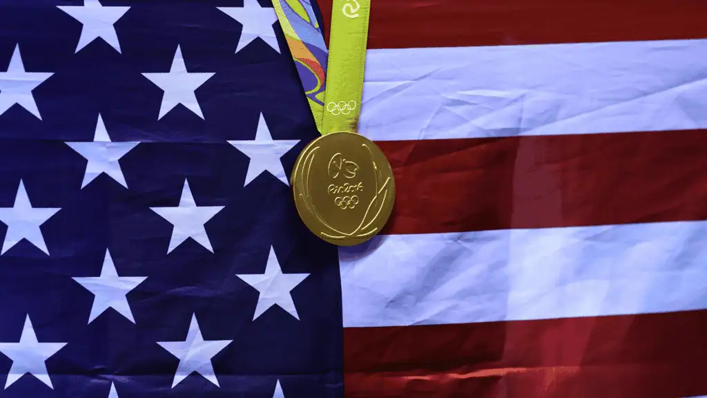 Blog 10 A gold Olympic medal hangs against the backdrop of the American flag, symbolizing victory and national pride.