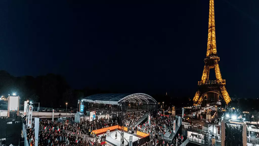 Blog 10 A lively night scene in Paris, featuring a crowded sports event near the illuminated Eiffel Tower amidst a vibrant atmosphere.