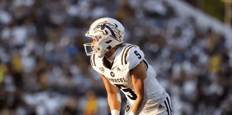 Football player in a white uniform with the number 5 and "Broncos" on the jersey, possibly in a game