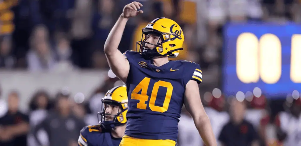 A football player in a blue and yellow jersey, number 40, prepares to throw a pass on the field during a night game.