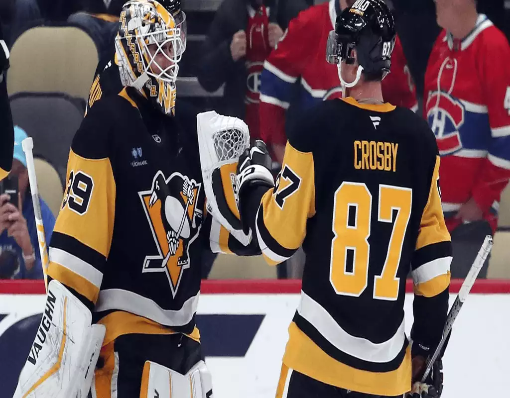 Pittsburgh Penguins players, goalie Matt Murray and captain Sidney Crosby, celebrate in their black and gold jerseys during a game.