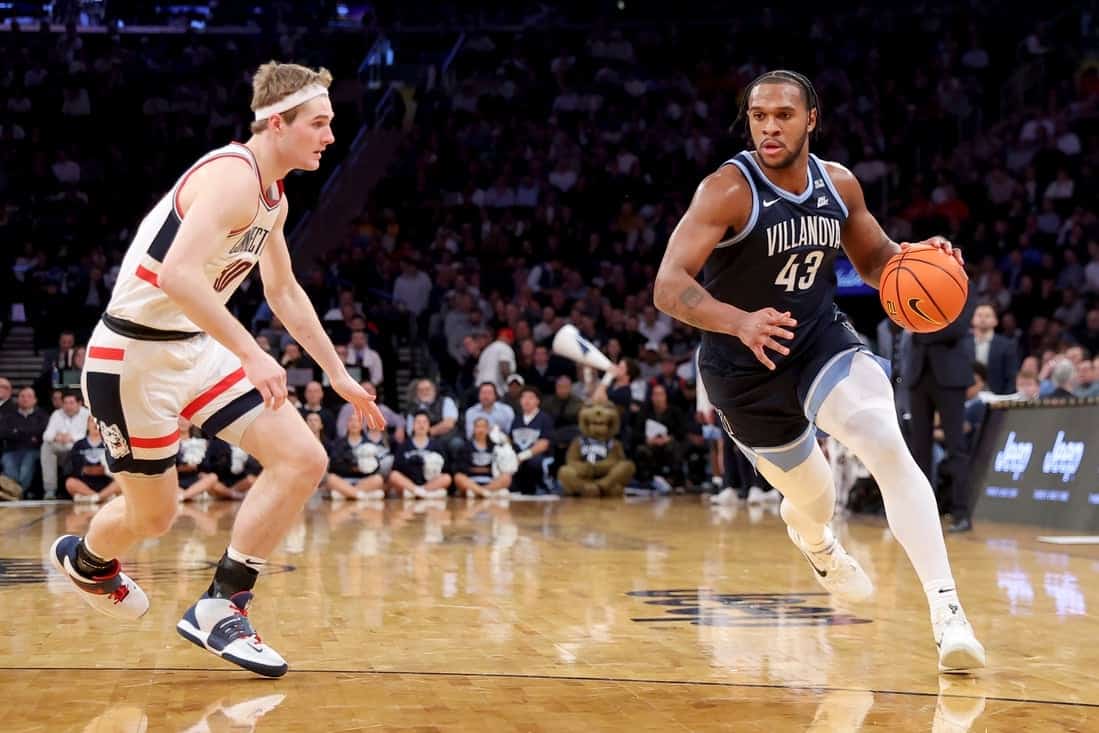 Two college basketball players competing on the court; one dribbling a ball in a Villanova jersey, the other closely guarding.