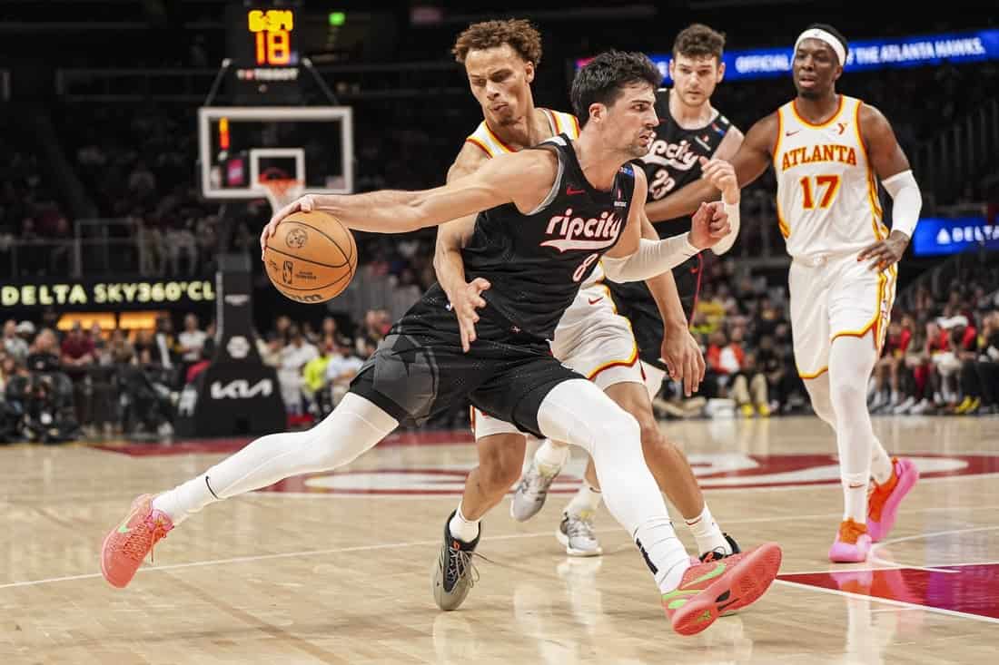 A basketball player in a black Rip City jersey dribbles the ball during a game, with teammates and opponents in action around him.