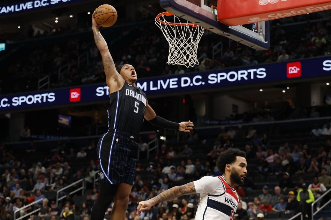 5 A basketball player in a blue Orlando jersey leaps for a dunk, showcasing athleticism above an opponent in a white jersey.