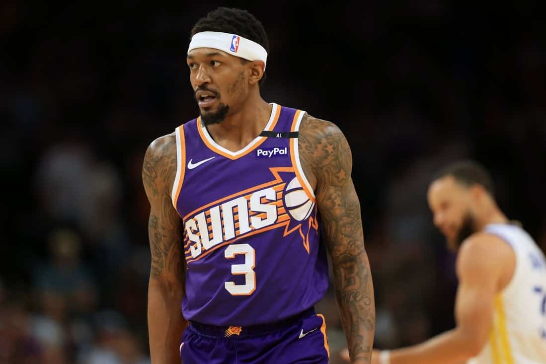 3 A basketball player in a purple Phoenix Suns jersey with the number 3 stands focused on the court during a game.