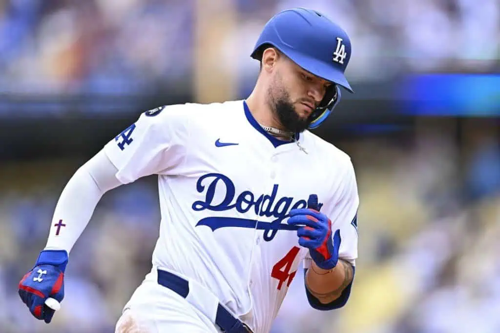 A Los Angeles Dodgers player in a white jersey and blue cap runs the bases during a game, showcasing team colors and intense focus.