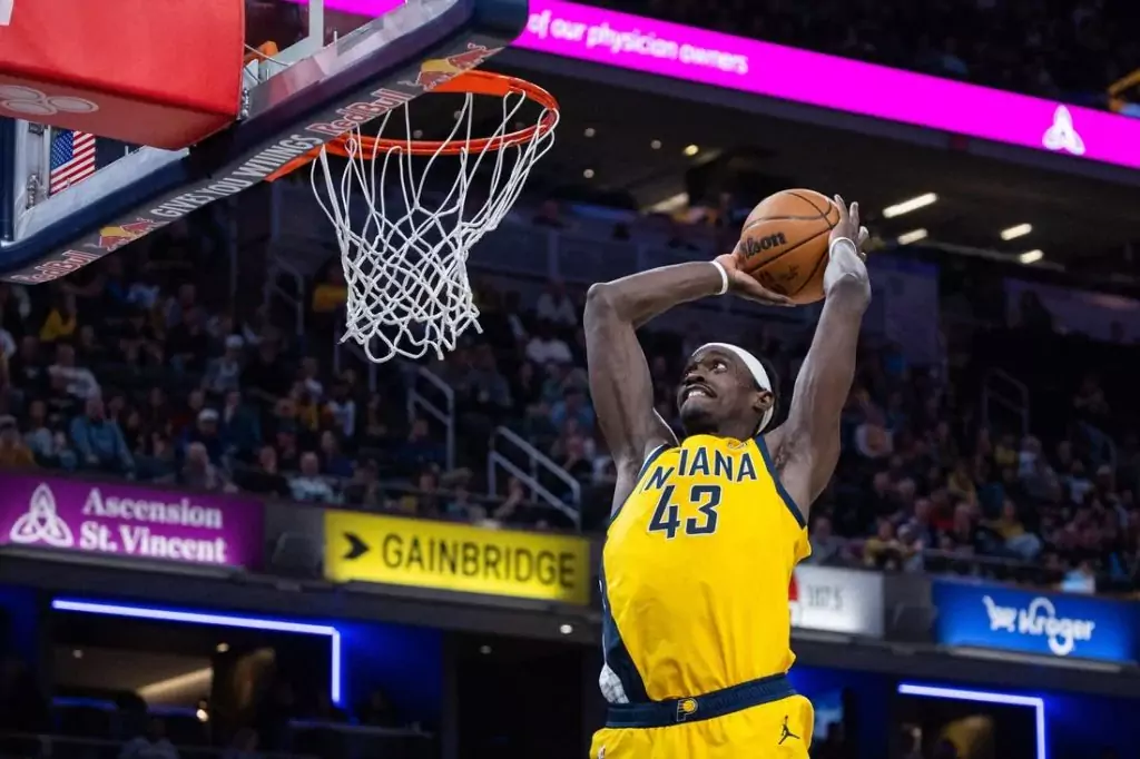 2 An Indiana Pacers player stands on the court in a white jersey, hands on hips, with fans in the background.