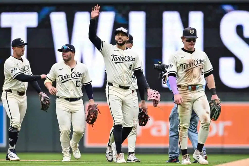 9 A group of baseball players in matching "Twin Cities" uniforms walk off the field, with one player waving to the crowd.