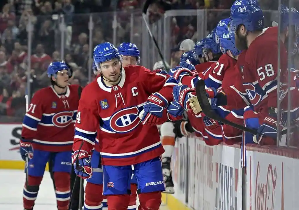 Montreal Canadiens players in red jerseys celebrate on the bench during a game, showcasing camaraderie and team spirit.