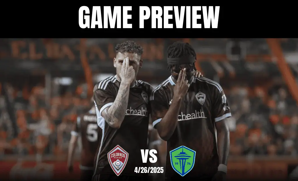 Two soccer players in brown jerseys are engaged in conversation against a blurred stadium backdrop, hinting at an upcoming match.