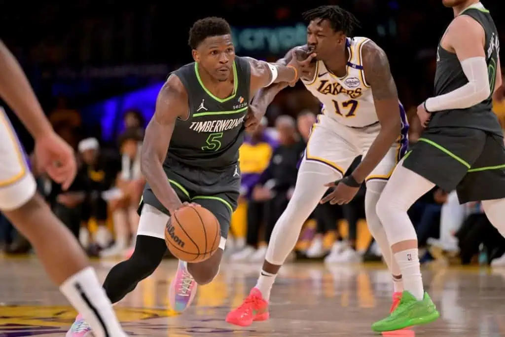 A basketball player dribbles the ball while being closely guarded during a game between the Timberwolves and the Lakers.