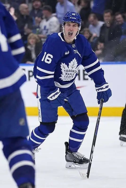 A Toronto Maple Leafs player skates on the ice, wearing a blue jersey with white stripes, focused on the puck.
