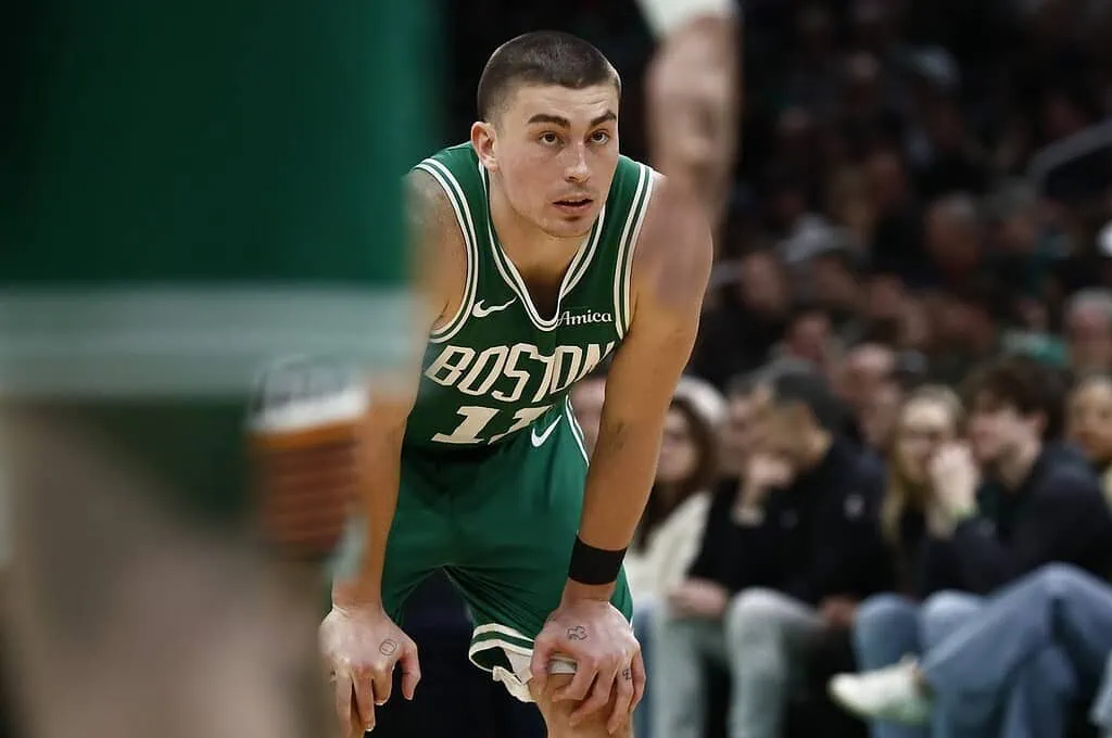 4 A basketball player in a green Boston Celtics uniform leans forward in exhaustion, with fans visible in the background.