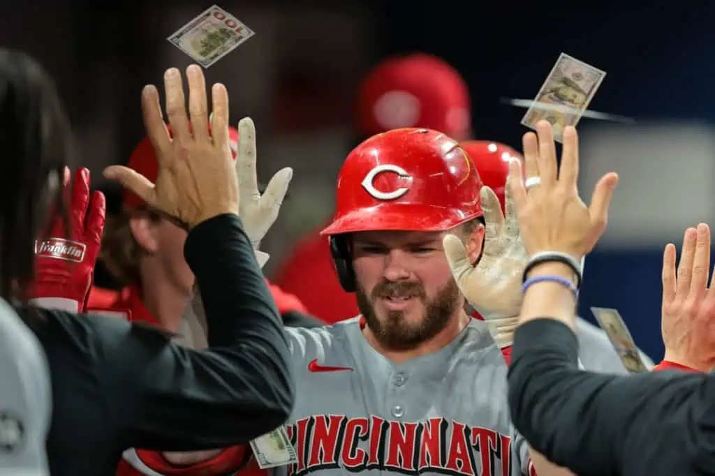A celebratory moment in baseball, teammates raise hands high as cash floats above, capturing the excitement of a successful play.