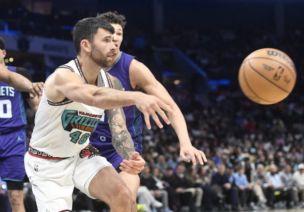 3 A basketball player in a Vancouver Grizzlies jersey passes the ball during an intense game, with spectators visible in the background.