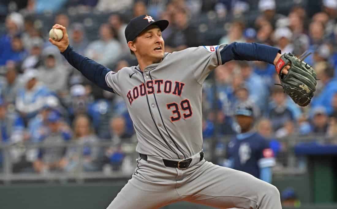 A Houston baseball player in a gray jersey, number 39, winds up to pitch on a field packed with fans in the background.
