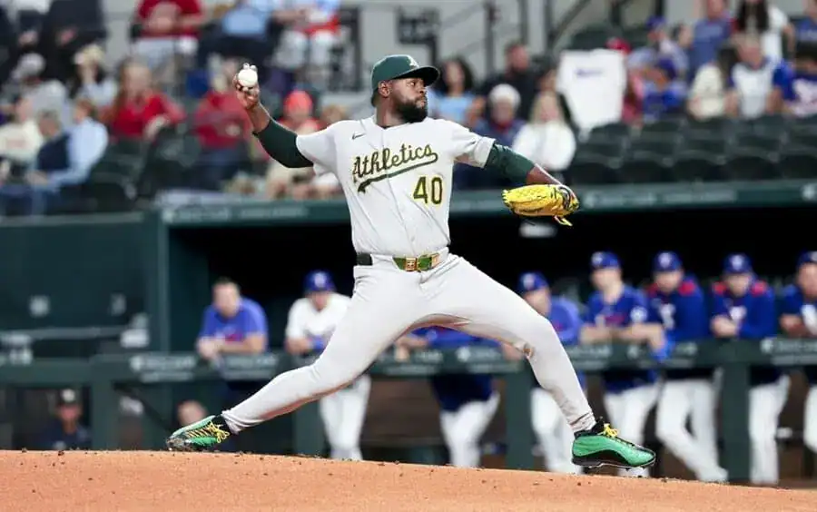 A baseball pitcher in a gray Athletics uniform is in mid-throw on the mound.
