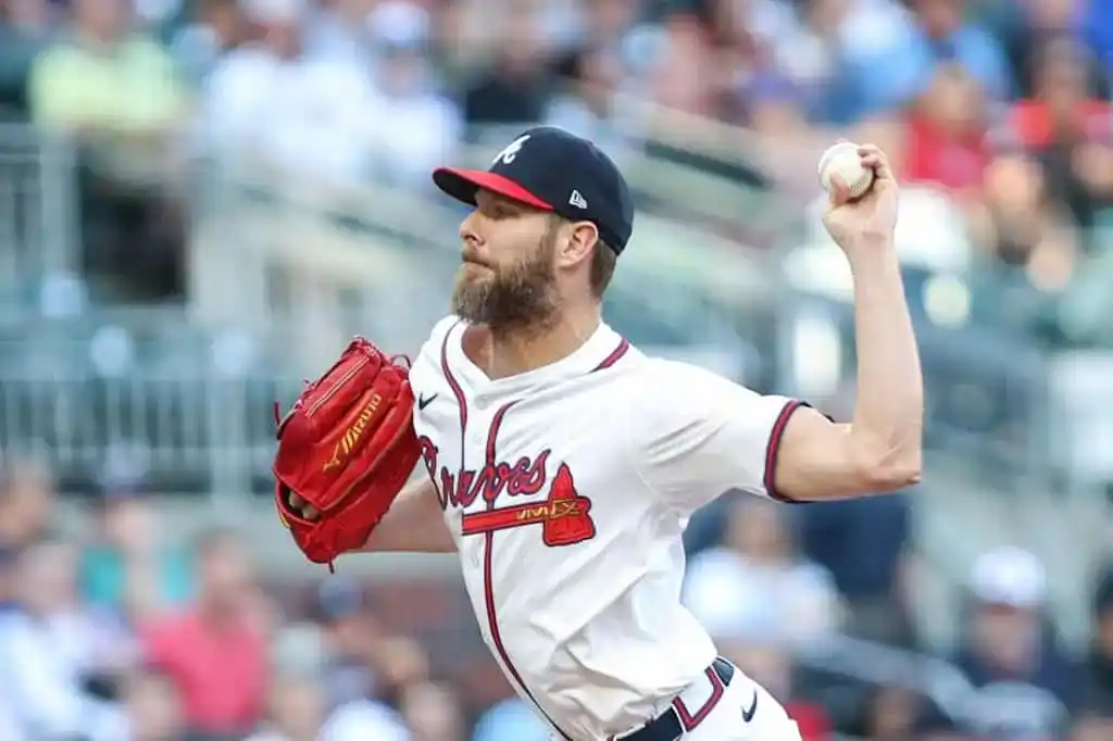 A baseball pitcher in a Braves uniform winds up to throw a pitch, showcasing a focused and athletic stance on the mound.