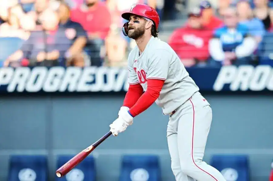 A Philadelphia Phillies player swings a bat during a game, with fans