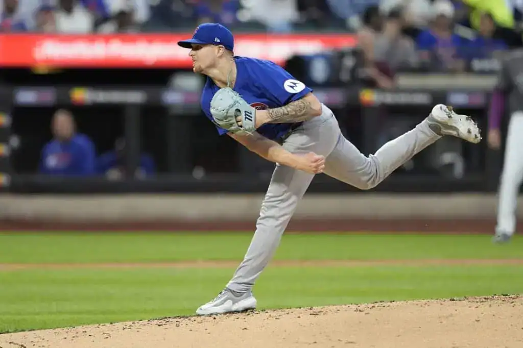 A pitcher in a blue jersey winds up to throw the ball on a baseball field, capturing a moment of intense athletic focus.