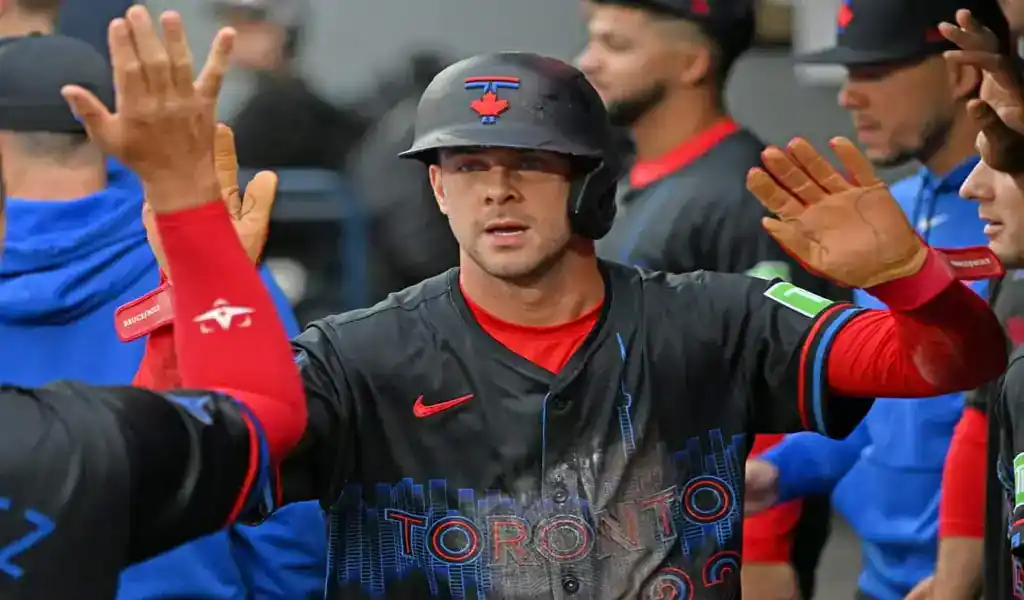 Toronto Blue Jays player celebrates with teammates after scoring against Oakland Athletics on