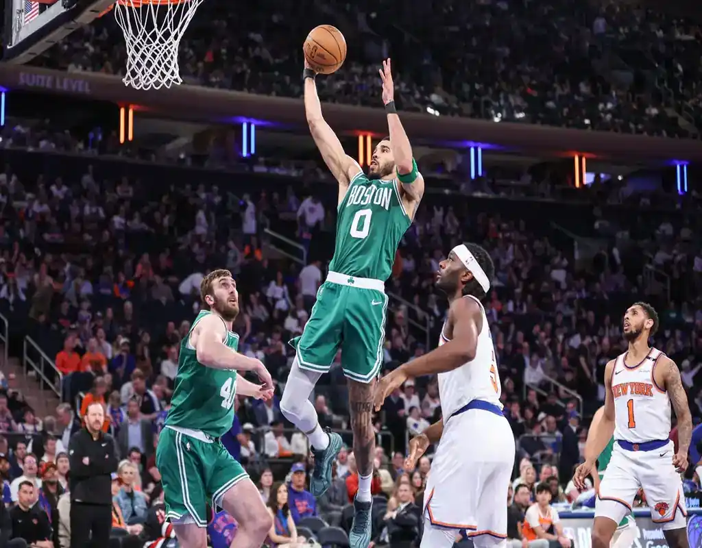 NBA game between the Boston Celtics and New York Knicks with action shot featuring a player driving to the basket during an intense matchup.
